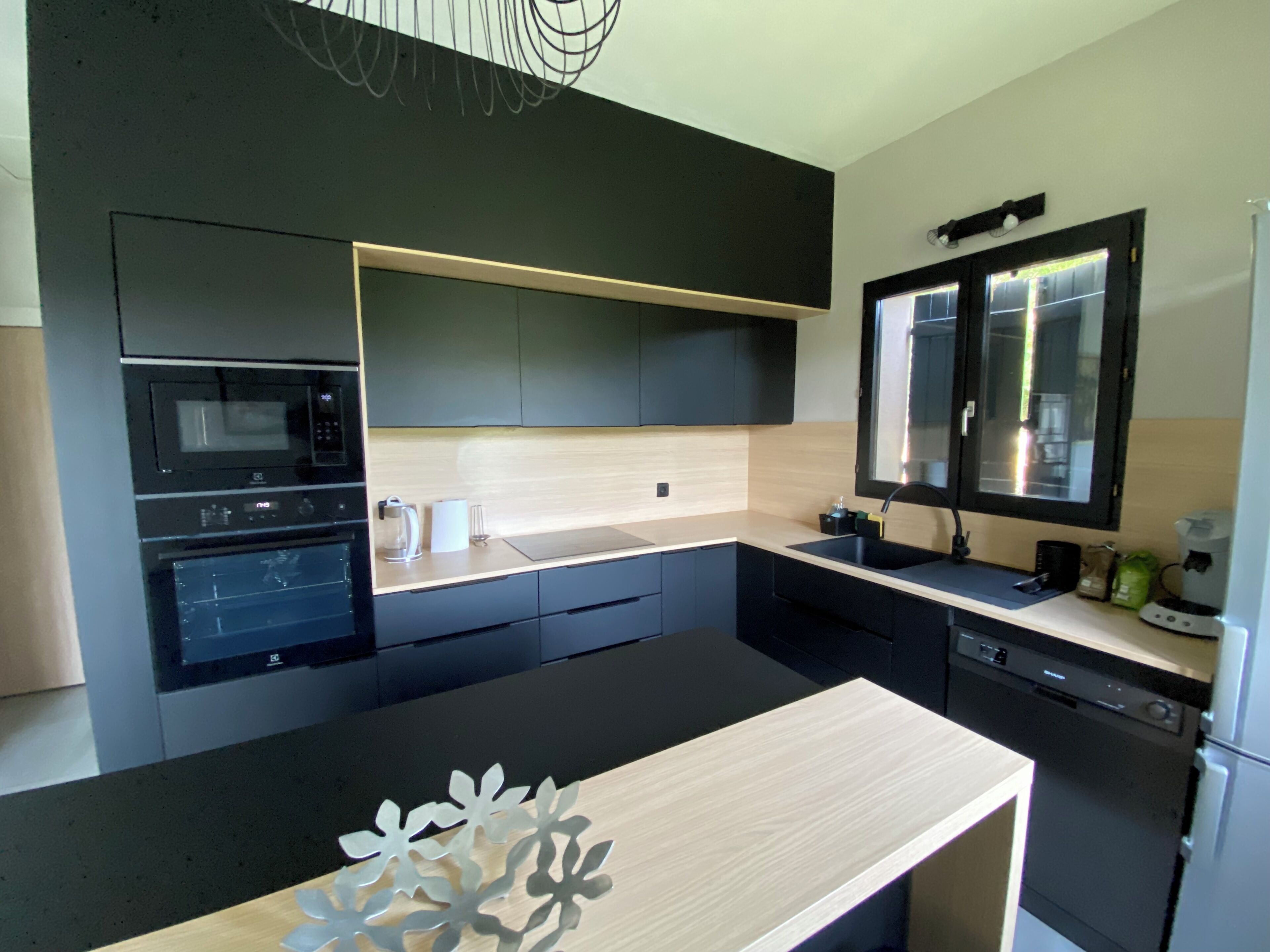 A modern kitchen with built-in appliances, a wooden countertop, and a black backsplash.