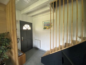 A staircase with wooden railings leading to a dark door with a semi-circular window. A painting is visible on the wall above the door. - Contemporary home with a view of the mountains (Pont de Montvert - Sud Mont Lozère)