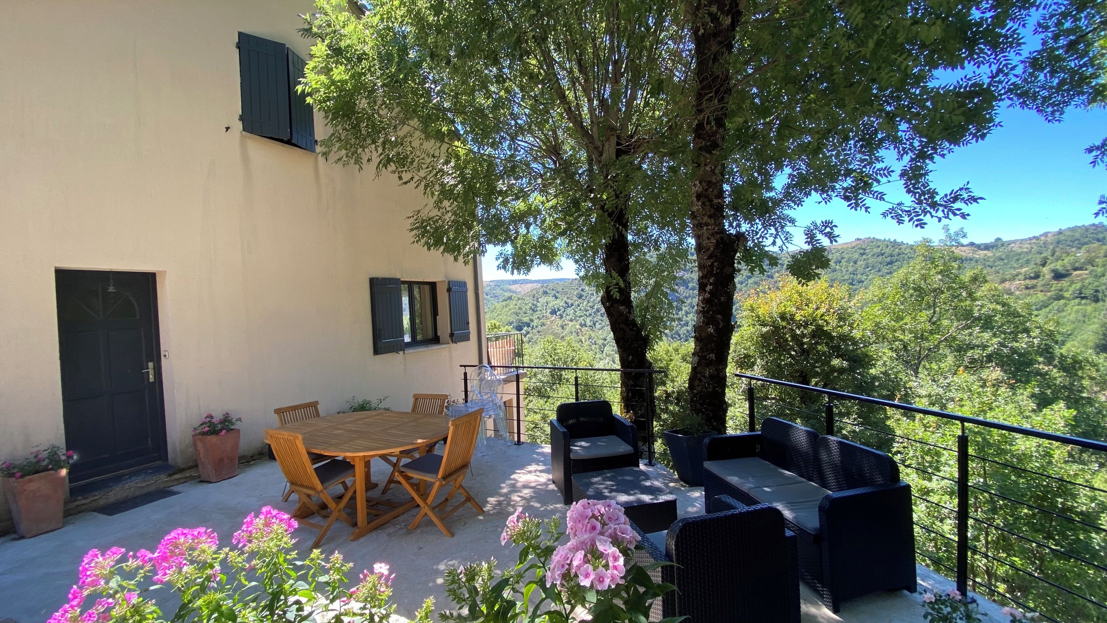 Une terrasse avec une table et des chaises, un canapé et une vue sur une colline.