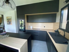 A modern kitchen with black cabinetry, a wooden countertop, and a built-in oven. - Modern House with a Mountain View (Pont de Montvert - Sud Mont Lozère)