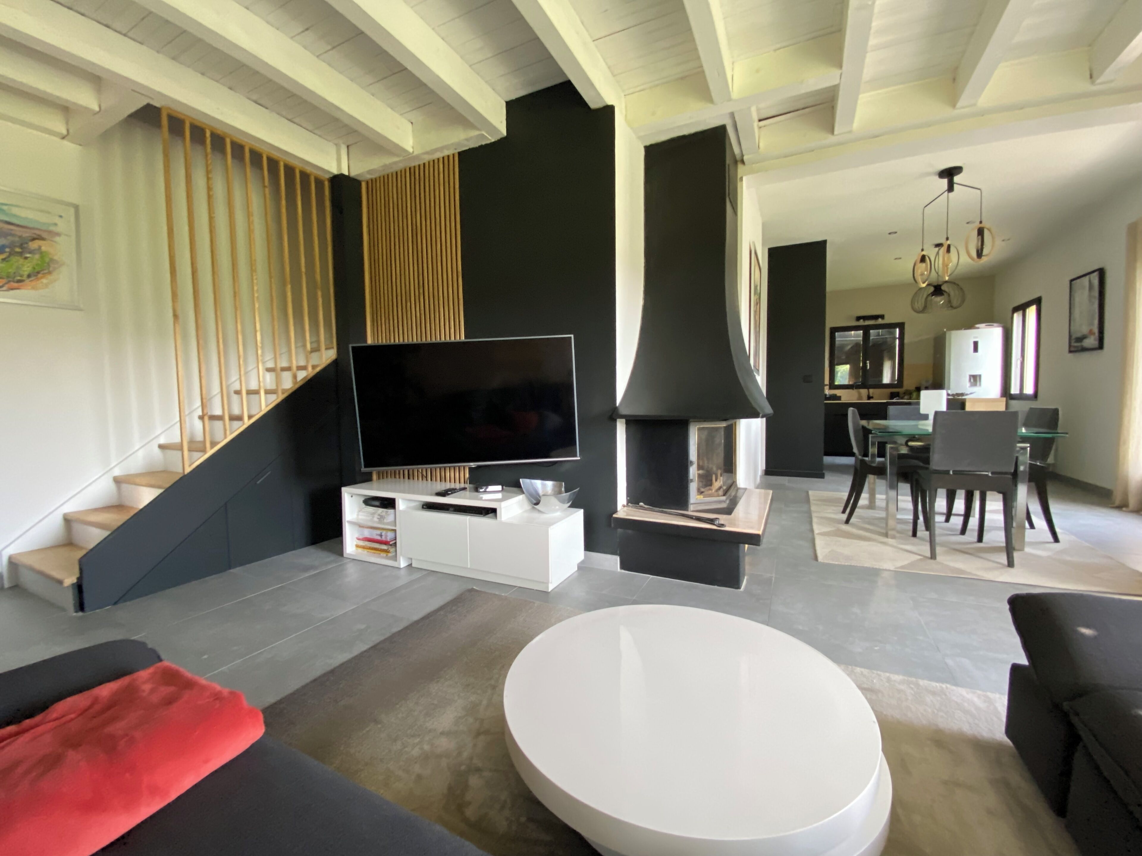 Un salon moderne doté d’un téléviseur à écran plat, d’une cheminée, d’un coin repas et d’un escalier.