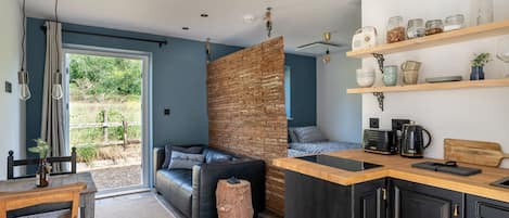 Una cocina moderna con encimera de madera, armarios negros y una pared de ladrillo decorativa.