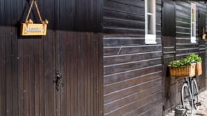 Un edificio de madera con un letrero que dice 'Bluebell', una bicicleta con cesta y un regador en el suelo.