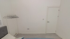 A bedroom with a bed, a grey headboard, a white door, and a wall-mounted drying rack. - 5 Gelli Terrace (Caerphilly)