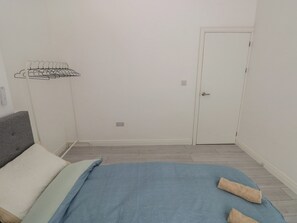 A bedroom with a bed, a grey headboard, a white door, and a wall-mounted drying rack. - 5 Gelli Terrace (Caerphilly)