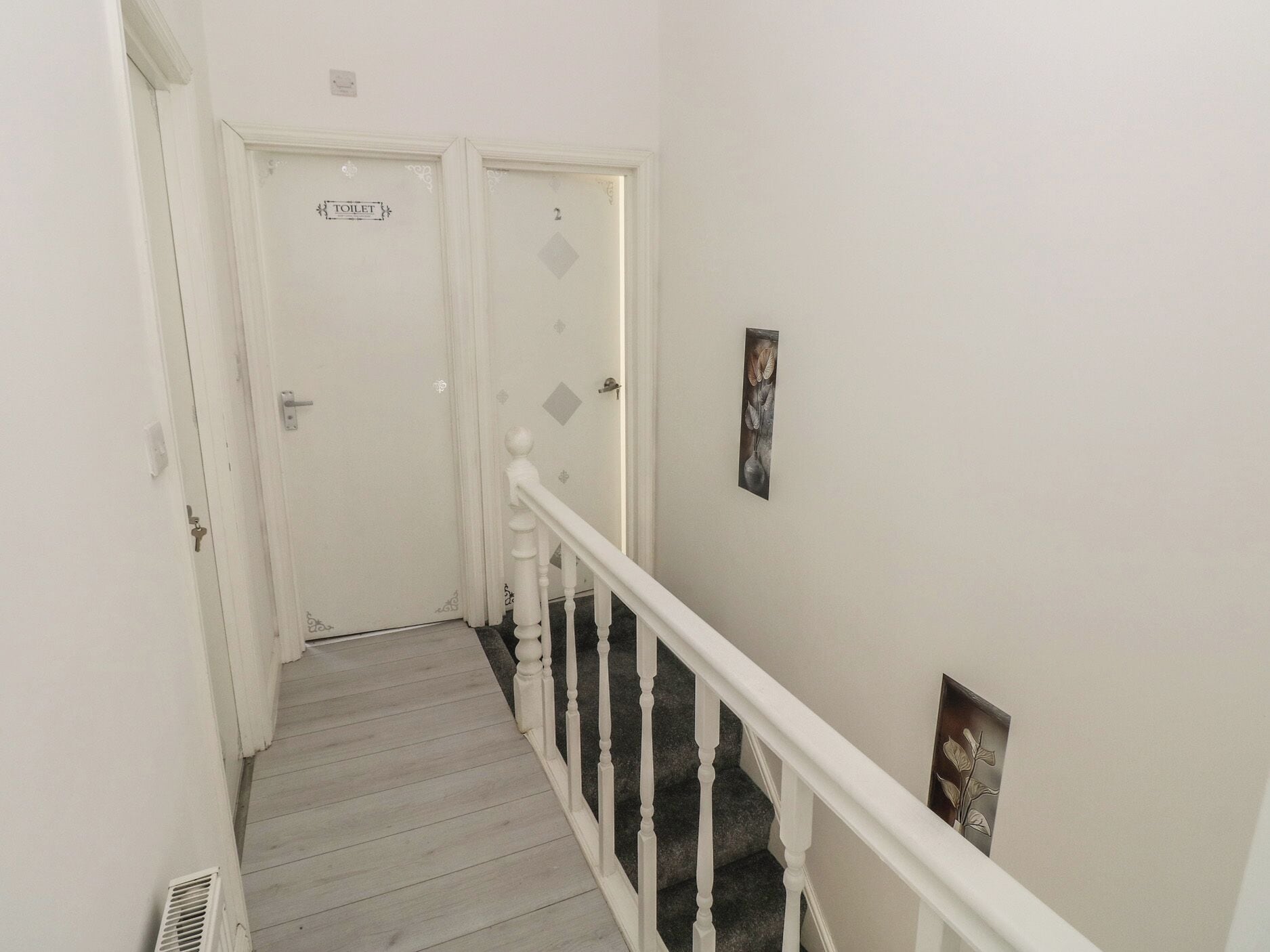A narrow staircase with white railings and a door labeled 'TOILET' at the top.