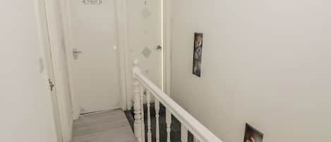 A narrow staircase with white railings and a door labeled 'TOILET' at the top.