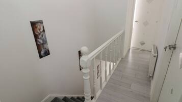 A staircase with a white railing, a door with a keyhole, and a framed picture on the wall.