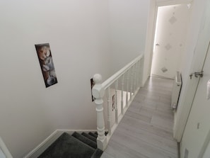 A staircase with a white railing, a door with a keyhole, and a framed picture on the wall. - 5 Gelli Terrace (Caerphilly)
