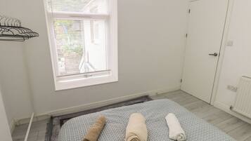 A room with a bed, a window with blinds, a door, and a radiator.