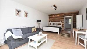 Un soggiorno moderno con un divano, un tavolino e un letto con testiera in legno.