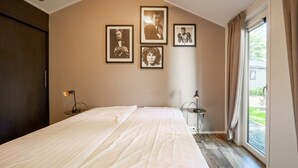 A bedroom with a bed, a window with curtains, and three framed pictures on the wall.