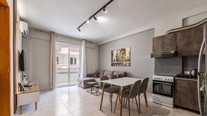 A modern apartment with a dining area, kitchen, and a large sliding glass door leading to a balcony. - Relax by the Sea | 1BR Apartment by PikHost (Durrës)