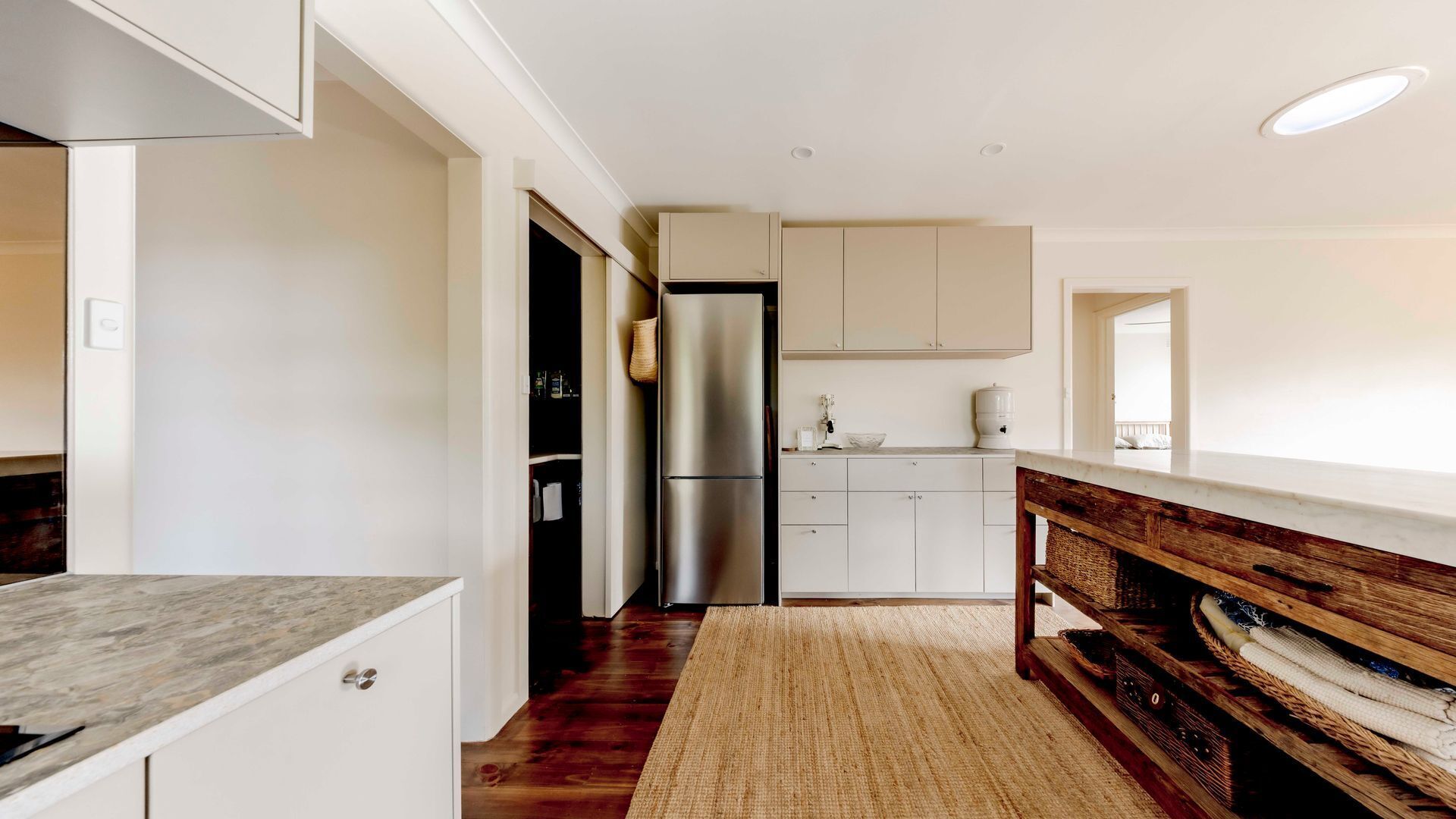 A modern kitchen with white cabinets, a stainless steel refrigerator, and a wooden countertop.