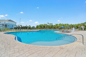 A swimming pool with a curved design, surrounded by lounge chairs and umbrellas, with a clear sky above. - Welcome to the Turles Nest at Lost Key Golf & Beach Club (Perdido Key)