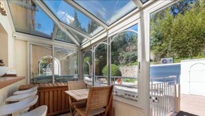 A conservatory with a glass roof, wooden furniture, and a view of the outdoors. - Penthouse sea View and Pool A/C 6P- Cannes (Cannes)