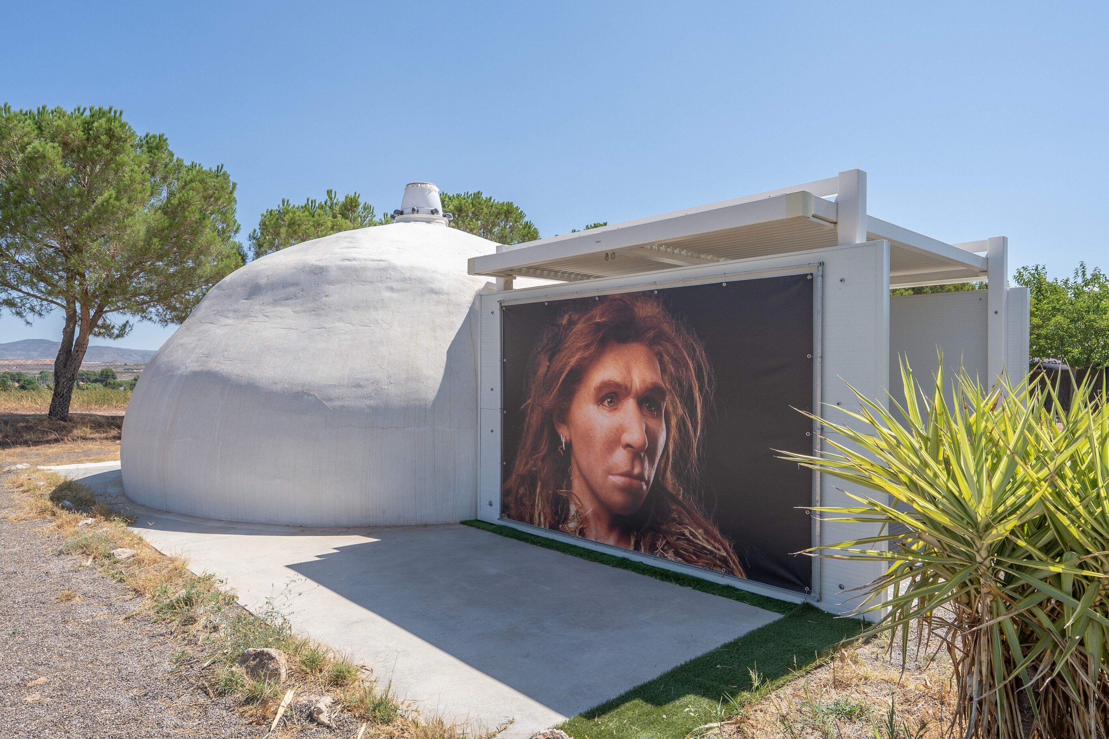 Una estructura moderna con techo abovedado y un gran mural en la pared.
