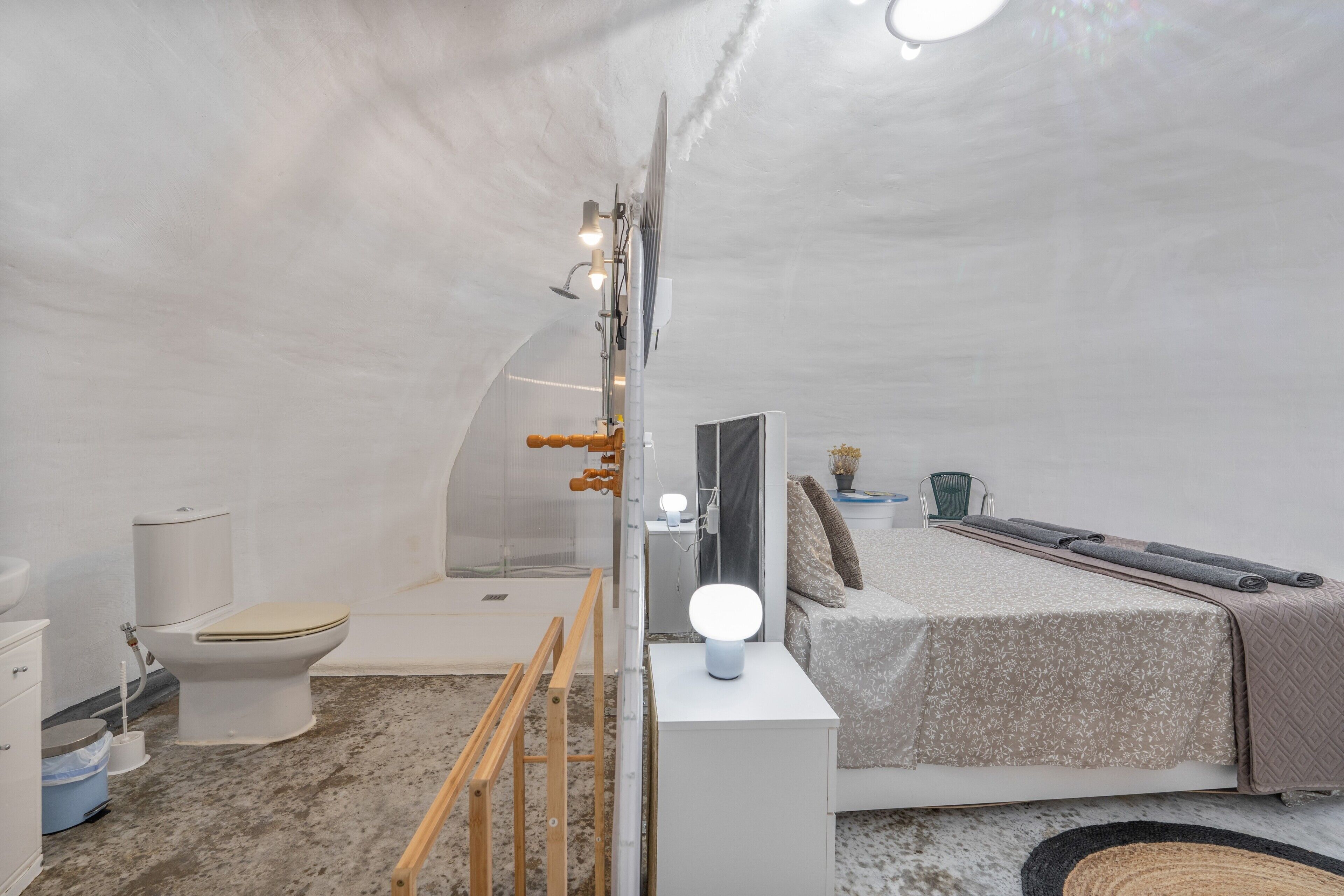 Dormitorio moderno y funcional con ducha, inodoro y cama con cabecera.