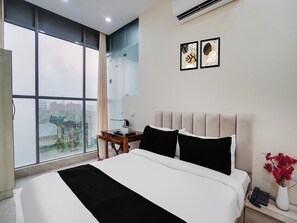 Ein Hotelzimmer mit einem großen Bett, einem Schreibtisch, einem Telefon und einer Vase mit Blumen.