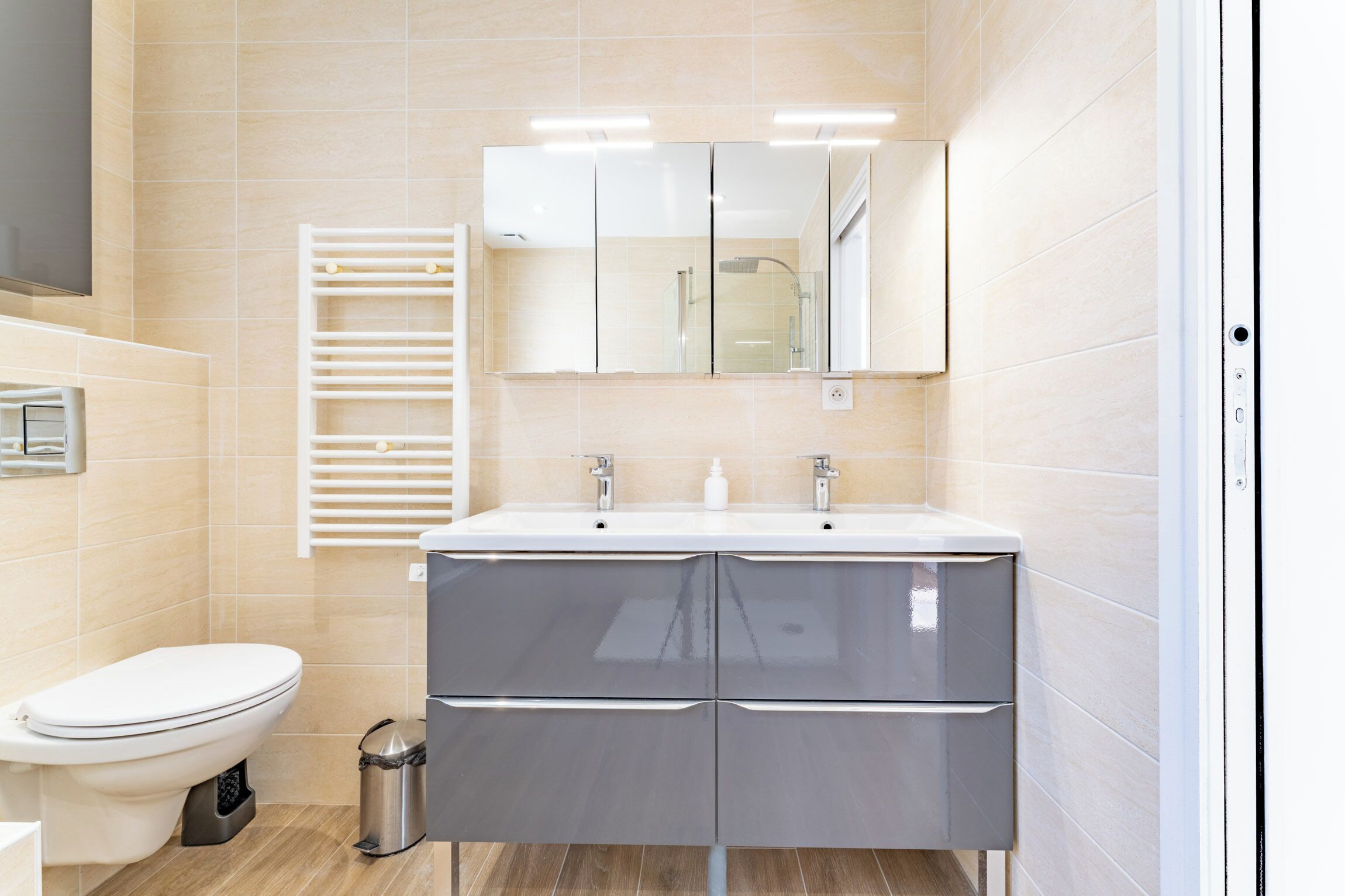 A modern bathroom with a toilet, a sink with a mirror, and a towel rack.