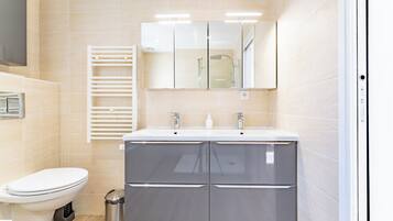 A modern bathroom with a toilet, a sink with a mirror, and a towel rack.