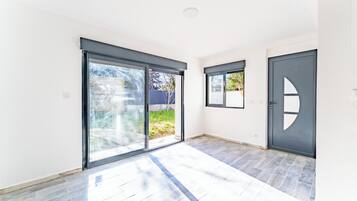 Een modern interieur met grote schuifdeuren, een donkere deur en een betegelde vloer.