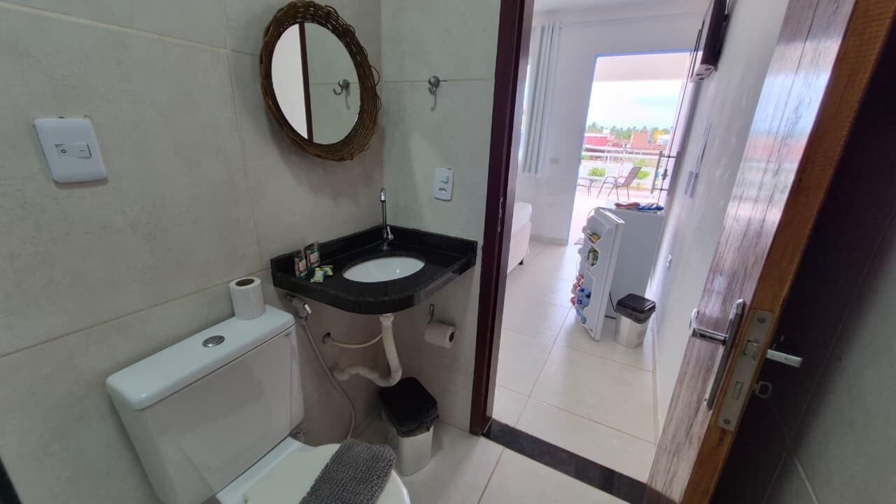 Un baño con inodoro, lavamanos, espejo y vistas al exterior.