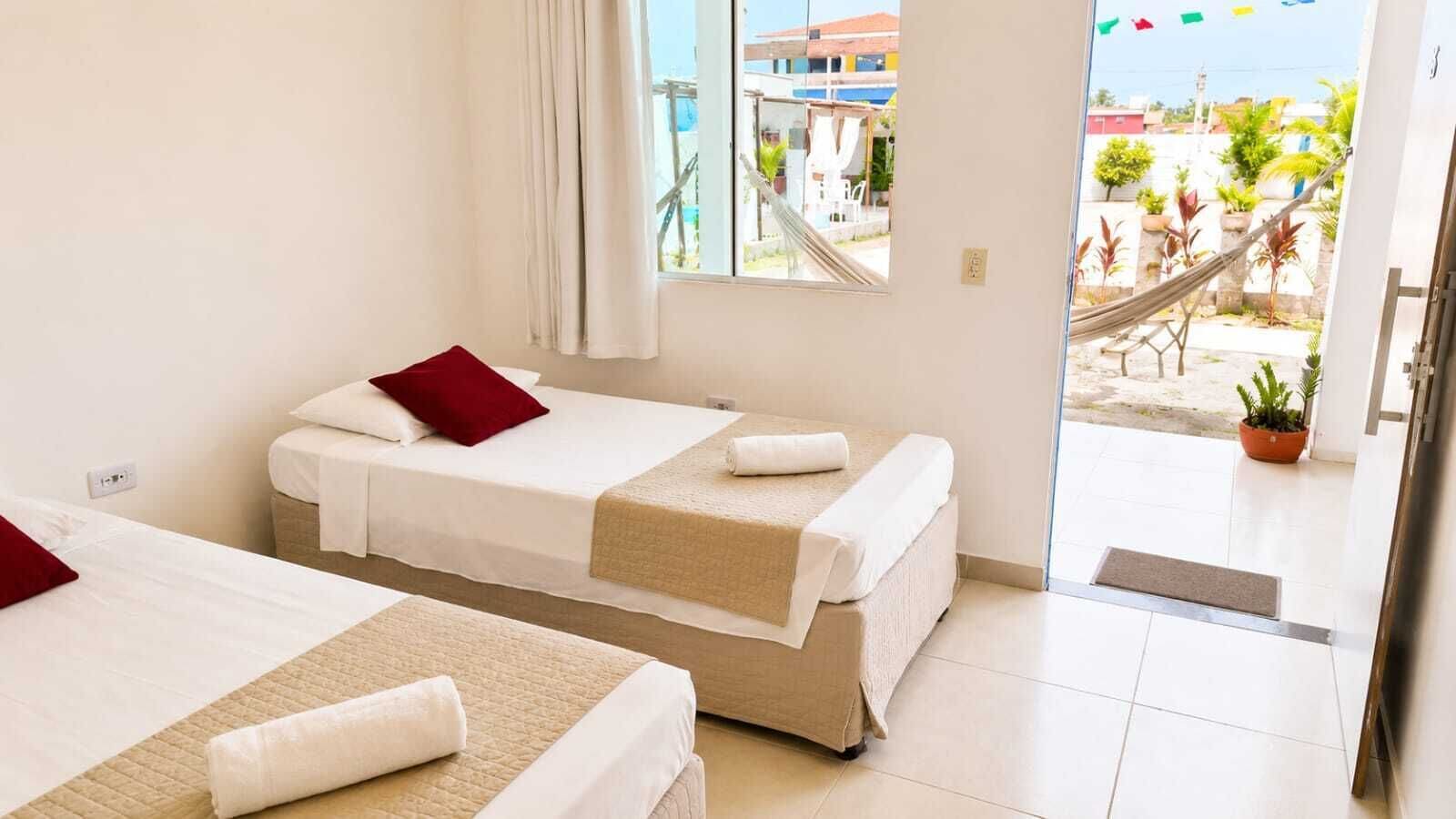 A hotel room with two beds, a window, and a view of the outside.