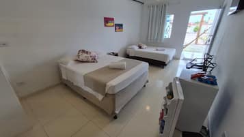 Habitación de hotel con dos camas, una mesita, una silla y una ventana con cortinas.