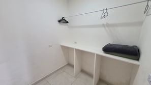 A small, white-walled room with a single white shelf and a black towel on it.