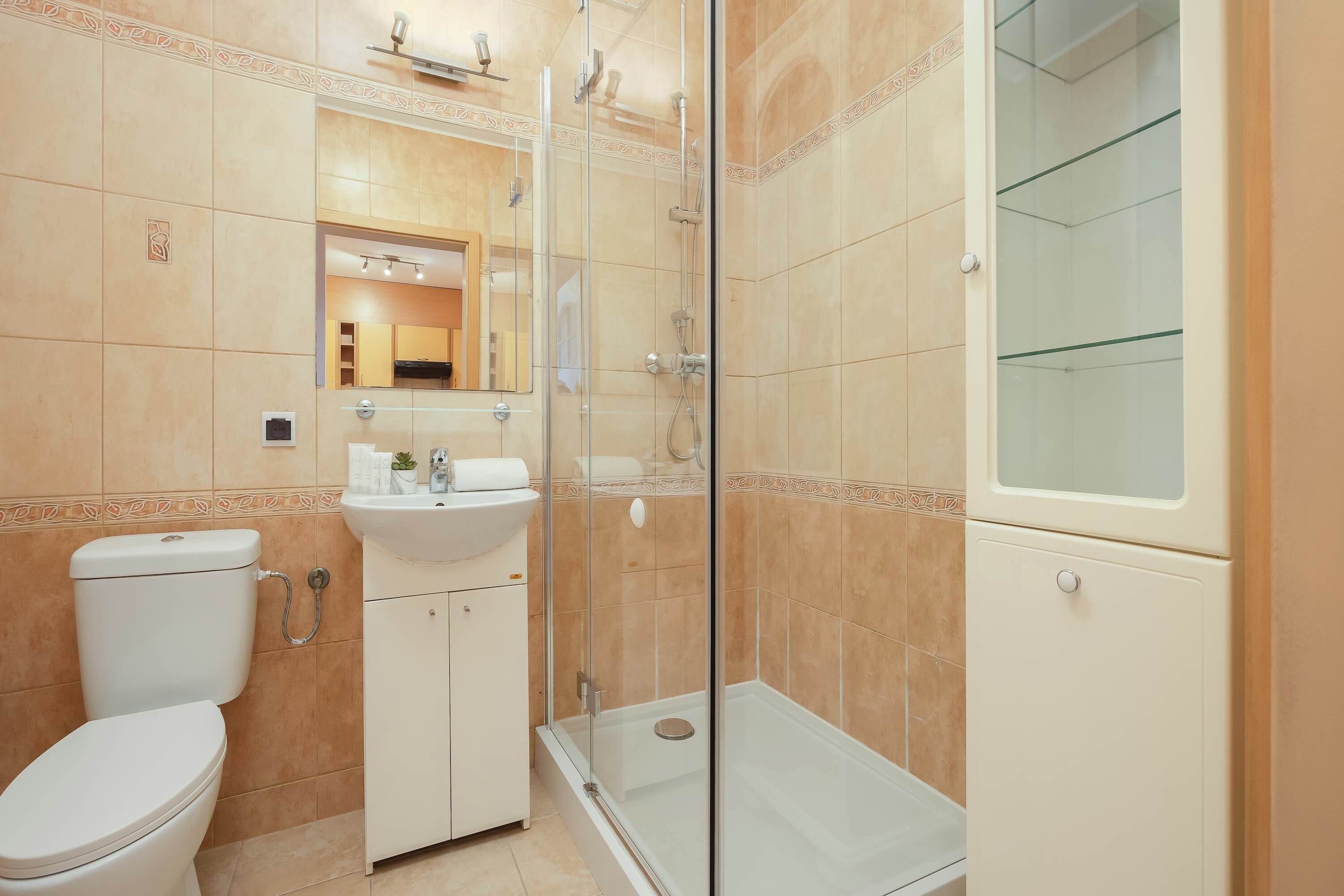 Une salle de bain comprenant des toilettes, un lavabo, une douche et une cabine de douche en verre.