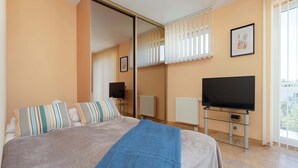 Una camera d'albergo con un letto, una televisione, una finestra con tende e un termosifone.