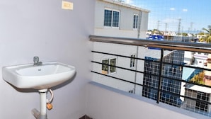 A small bathroom with a white sink, a window with a view of buildings, and a metal railing.