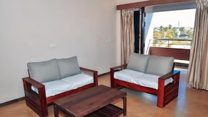 A room with two wooden sofas, a wooden coffee table, and a large window with curtains.