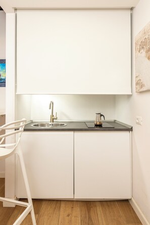 A modern kitchen with a stainless steel sink, a kettle, and a white chair. - San Francesco Ripa Apartments (Roma)