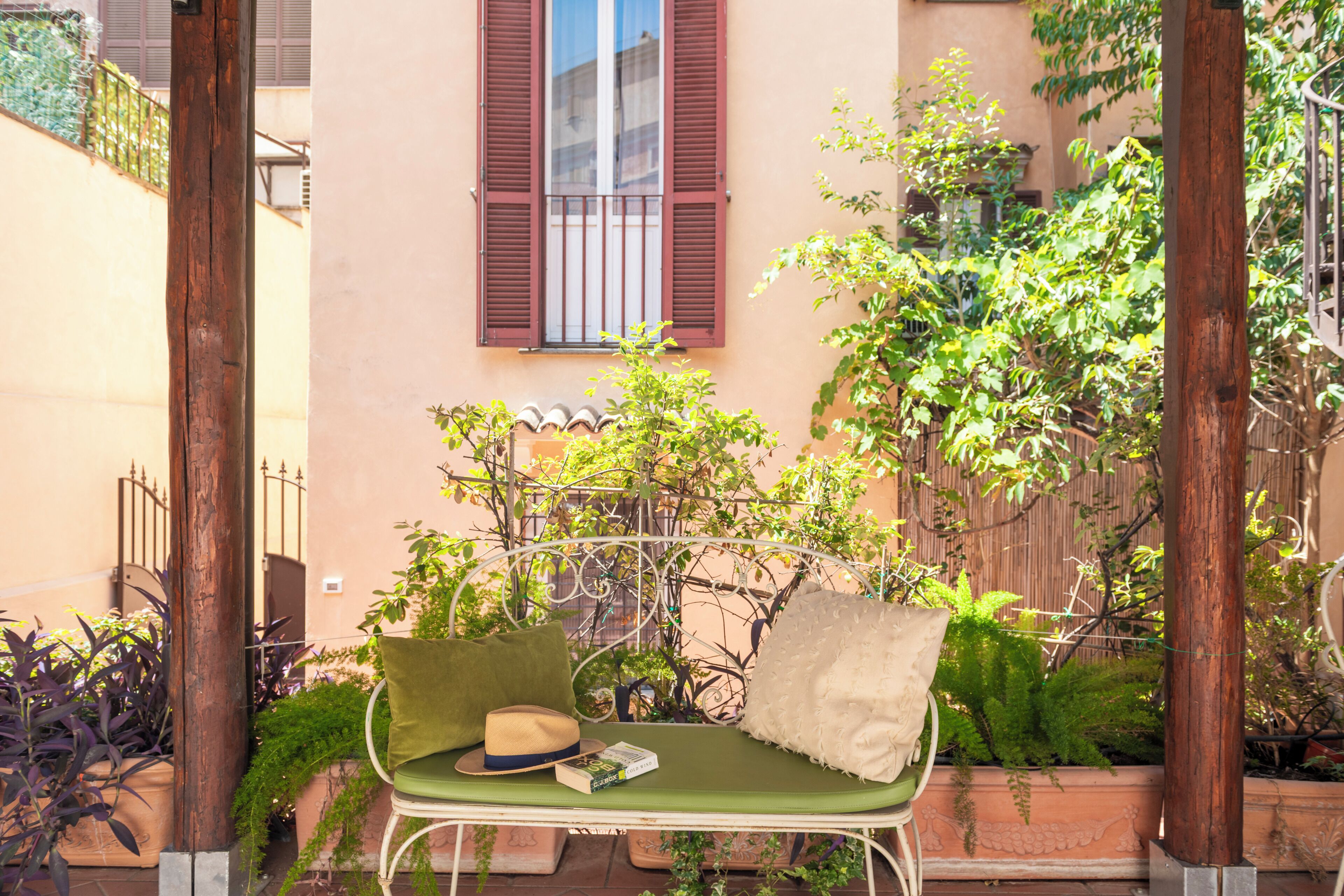 A green outdoor seating area with a bench, a hat, and a book titled 'Cold Wind'.