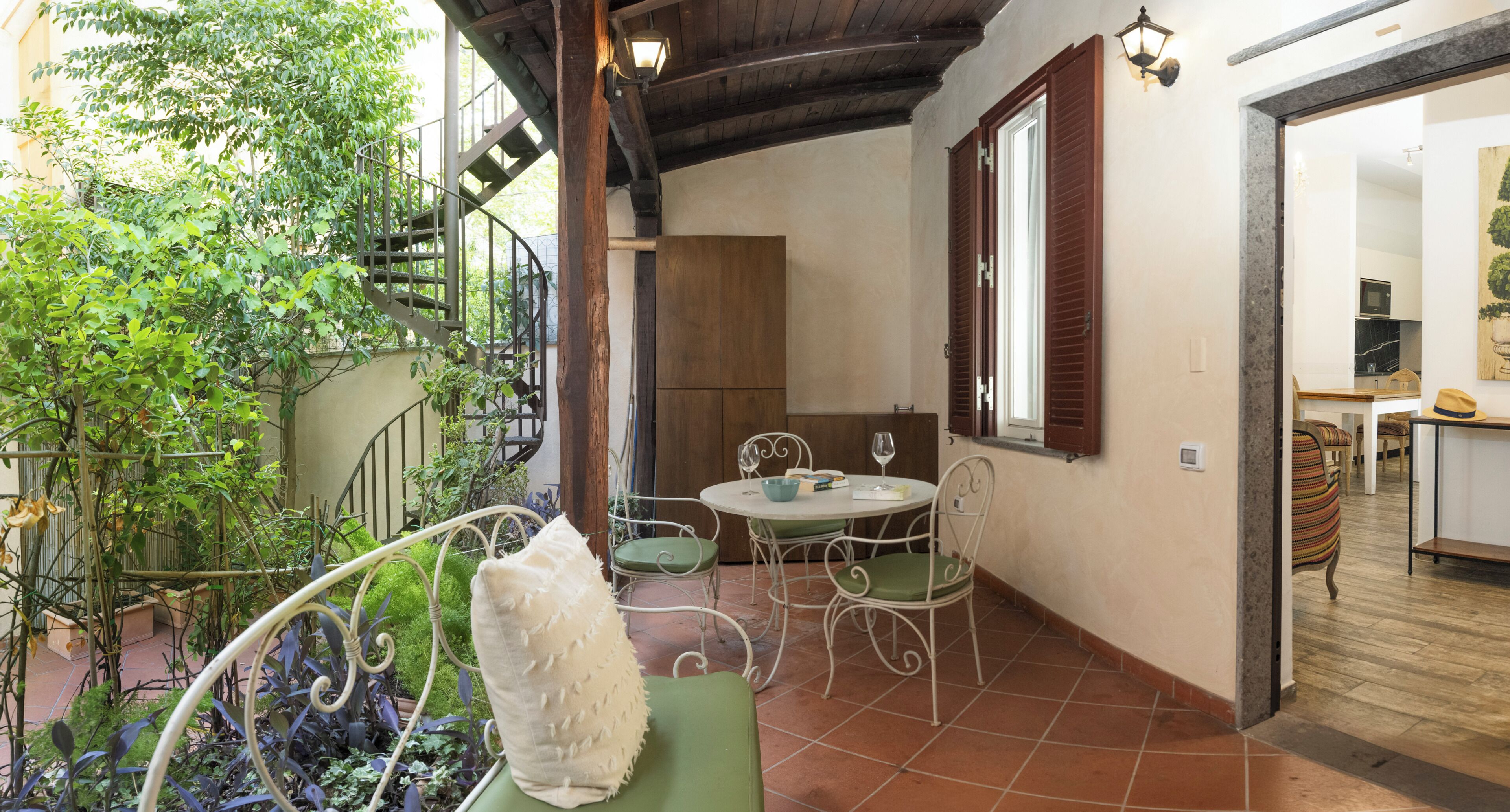 A dining area with a table and chairs, a staircase, and a view of the outside.