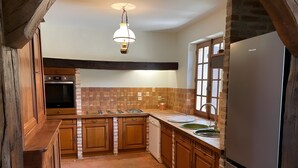 A kitchen with wooden cabinets, a built-in oven, a refrigerator, and a hanging light fixture.