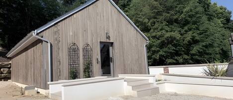 A wooden building with a sloped roof, a door, and a small set of steps leading to the entrance.