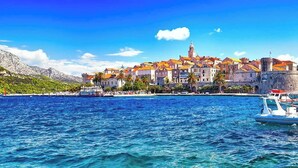 Une ville côtière dotée de bâtiments historiques, d’une mer d’un bleu limpide et de bateaux.