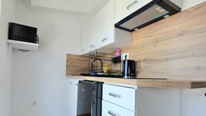 Eine kompakte Küche mit weißen Schränken, einem schwarzen Geschirrspüler und einer Holz Arbeitsplatte.