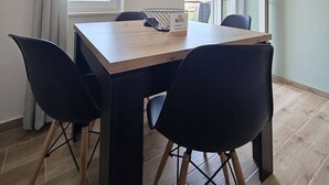 Un espace repas avec une table en bois, des chaises noires, un panneau indiquant la présence d’une connexion Wi-Fi et une horloge au mur.