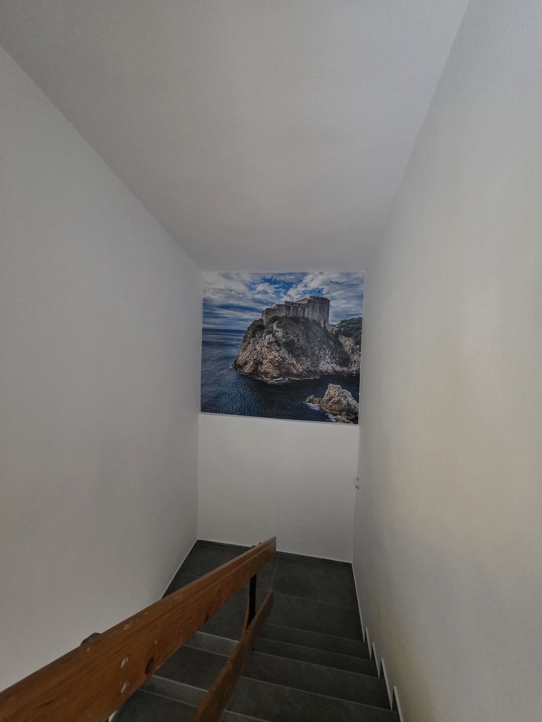 A staircase with a view of a rocky coastline and a building on top.