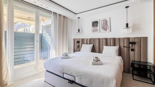 A modern bedroom with a large bed, a sliding glass door to the outside, and a small bedside table. - Luxurious Apartment - Croisette/hotel Mondrian (Cannes)