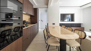 A modern kitchen with built-in appliances, a dining area with a large table and chairs, and a TV mounted on the wall. - Luxurious Apartment - Croisette/hotel Mondrian (Cannes)