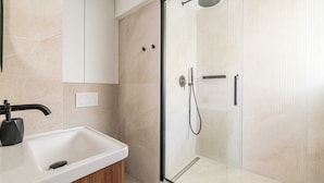 A modern bathroom with a glass-enclosed shower, a white sink, and a wooden cabinet. - Luxurious Apartment - Croisette/hotel Mondrian (Cannes)