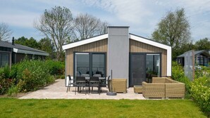 A modern house with a patio, outdoor furniture, and a large window. - Pavilion Waterfront 6 (Bovenkarspel)