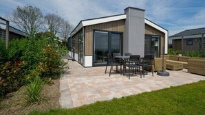 A modern house with a patio, outdoor furniture, and a garden. - Pavilion Waterfront 6 (Bovenkarspel)