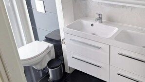 A modern bathroom with a toilet, bidet, sink, and storage drawers. - Pavilion Waterfront 6 (Bovenkarspel)