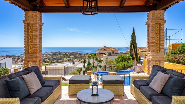 A covered outdoor seating area with wicker furniture, a table, and a view of the sea. - Spacious 5-bedroom villa with Top views and heated pool in charming Benalmádena (Benalmádena)